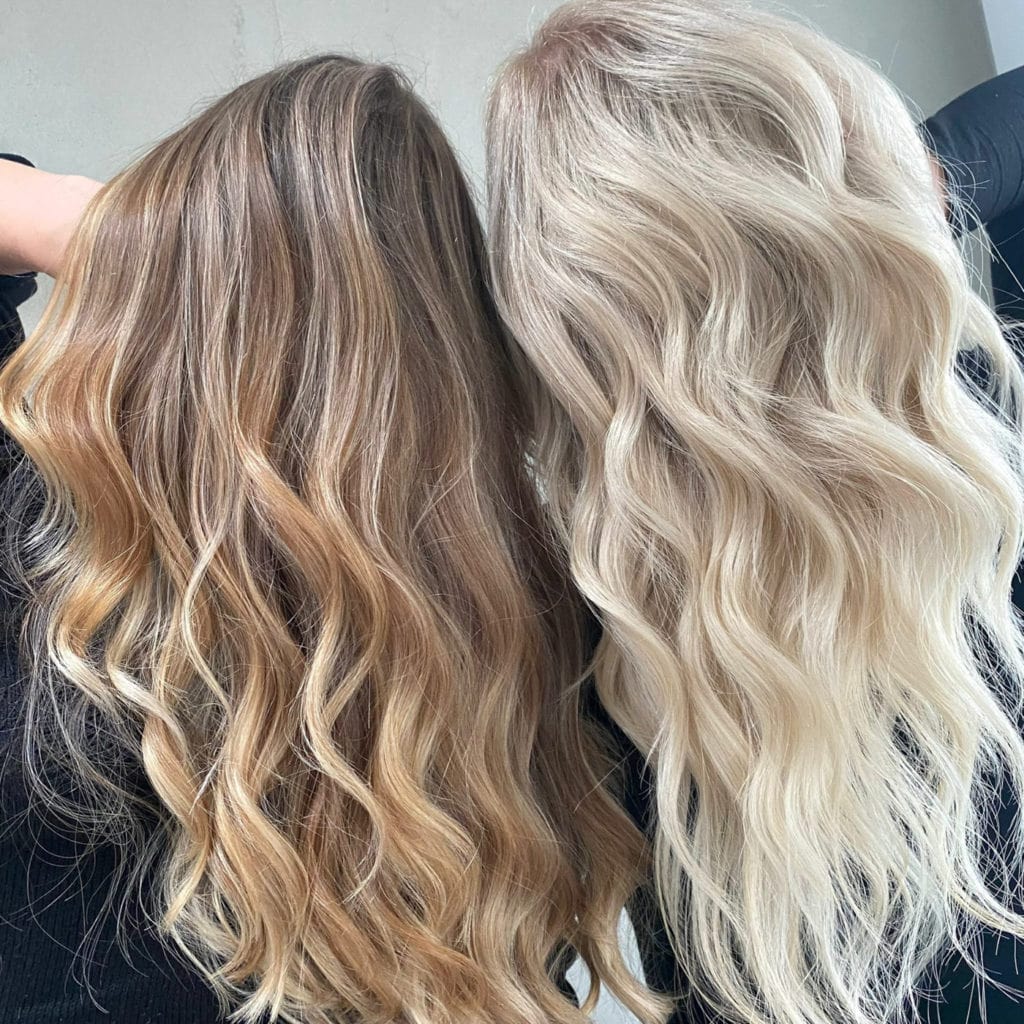 Zwei Frauen, die ihre Frisuren prÃ¤sentieren. Die eine hat lange brÃ¼nette gelockte haare und die andere hat lange, blonde, gelockte Haare. Beide wurden mit der Balayagetechnick gefÃ¤rbt.